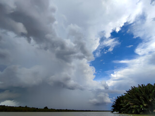 A view of thick clouds pouring heavy rain over the land and river below, creating a misty atmosphere.