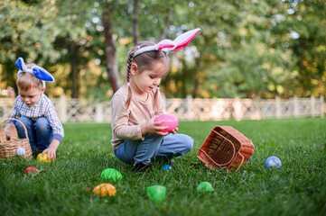 Children Collecting Easter Eggs Outdoors in Bunny Ears