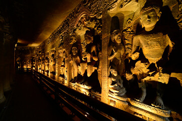 Interior of one of the Ajanta caves depicting Hand sculpted stone statues of Buddhist deities, Maharashtra, India.
