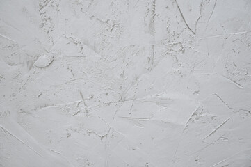 Textured white background with putty applied. The surface has a matte shade, natural irregularities...