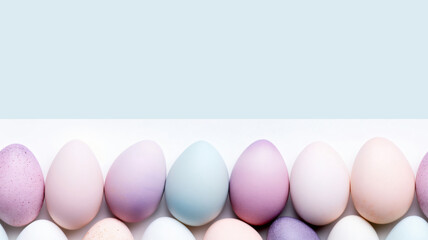 Colorful Easter Egg bottom border over a blue paper banner background. Copy space and seamless edges.