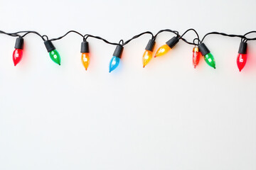 Christmas lights dangling on a white backdrop.