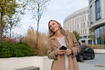 A businesswoman walks past a modern business center while looking at her phone