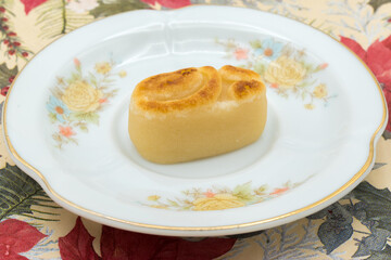 Plate with a marzipan figure, on a tablecloth with a Christmas pattern.