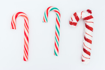 Group of three traditional holiday candy cane striped in christmas colours (one red and white; one green, red and white; one is a stuffed candy) isolated on white background.