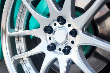 Alloy wheel plug rim rods and aqua green brake caliper selective focus close up.