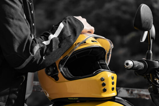 Close-Up of Yellow Motorcycle Helmet and Biker's Hand in Black and White Background