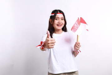 Smiling young Asian woman with red white flag and ribbon holding flag indonesian to celebrating...