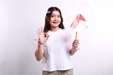 Smiling young Asian woman with red white flag and ribbon holding flag indonesian to celebrating...