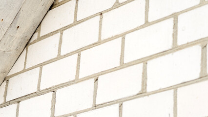 A white brick wall with a white roof is the main focus of the image. The wall is made up of individual white bricks, and the roof is also white. The wall appears to be part of a building