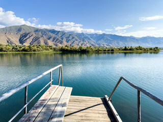 A wooden pier on Issyk-Kul lake with a view of the mountains. A beautiful spot for relaxation and...