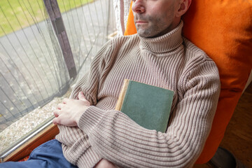 Young man relaxing with book on windowsill in old house, reclining on windowsill, self-reflection,...