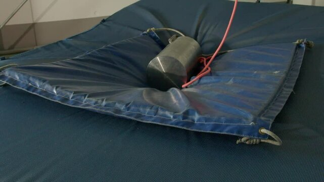 A heavy mass falls from above in slow motion and crushes a mattress, laboratory experience