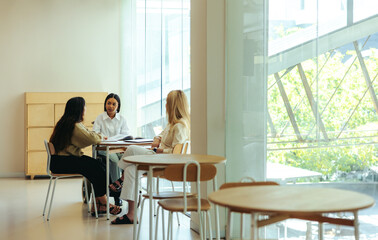 Obraz premium Women engaged in an informal meeting in a modern educational setting in the city, filled with natural light and open space