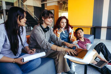 Casual group of young adults collaborating on a project with laptops in a contemporary office...
