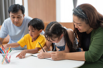 Fototapeta premium Asian parents teaching and helping kids to do homework at home, family spending time together. mother and father taking care of son and daughter. support knowledge and education