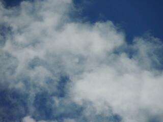 white cumulus cloud on blue sky in blurry focus as natural airy texture, floating light clouds on bright sky vault as background backdrop full frame
