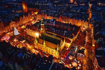 Aerial view of Christmas market at night with illuminated stalls, festive tree and historic...