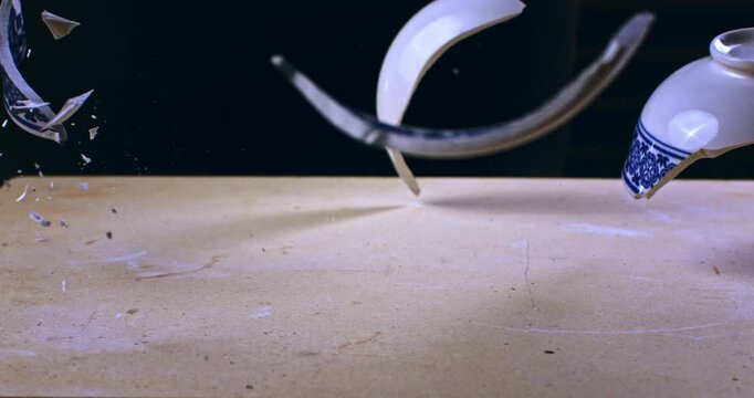 Super slow motion close up of ceramic bowl falling and shattering into many pieces against hard surface at 1000 fps.