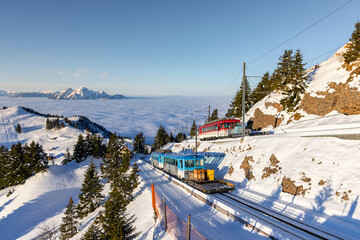 blue and red rigibahn trains are climbing the summit of mount rigi