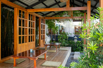A Japanese-style restaurant with wooden tables and tatami mats, surrounded by a bamboo garden.