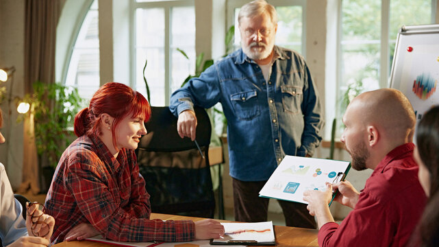 Diverse team in corporate environment, reviewing reports and data to set business objectives and align on strategies. Close up. Concept of business, consultation, marketing, management. Ad