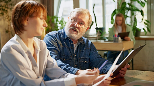 Experienced team leader explains charts and graphs, helping colleagues understand financial data and growth trends Concept of business, consultation, marketing, management, experience and success. Ad