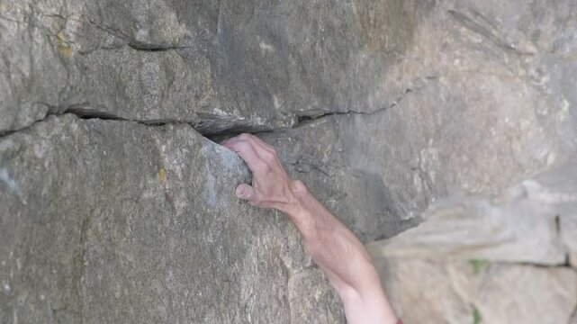 A climber's hand reaching for a grip in a rocky crevice during an outdoor climbing session in the mountains