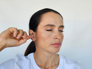 Woman scratching inside of ear with finger