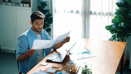 Naklejka premium Skilled businessman writing idea on colorful sticky notes while looking at data analysis. Caucasian project manager working on laptop while taking a note in sticky notes at meeting room. Convocation.