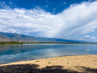 A wooden staircase leading into the clear waters of Issyk-Kul lake, with visible underwater vegetation. A perfect spot for water relaxation and enjoying nature