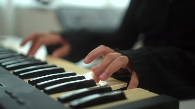 Close up hand of young musician woman playing piano while sitting in digital recording studio home, a composer female mastering music audio for soundtrack live performance with piano keyboard.

