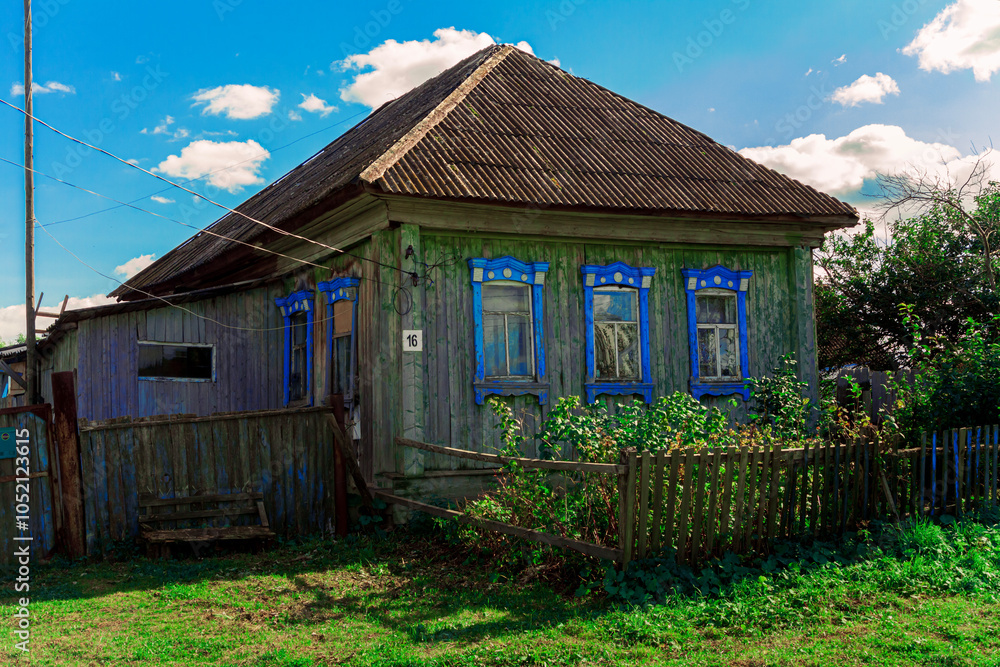 Wall mural Old houses. Carved window frames. View of a fragment of a house wall with carved decorations around the window and doors. Traditional Russian old houses. Close-up. Front view. Landscape.