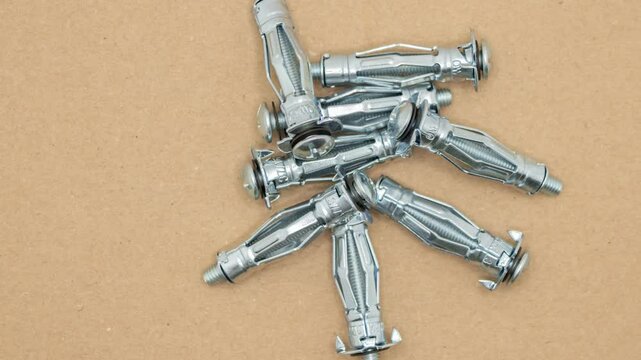 Closeup of Several new shiny molly bolts are lying on a brown surface