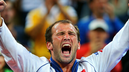 Male athlete celebrating victory, ecstatic emotion, raising arms in a sports arena