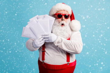 Portrait of his he nice attractive amazed wondered overwhelmed thick white-haired Santa holding in hand many mail gift wish list lottery isolated bright vivid shine vibrant blue color background