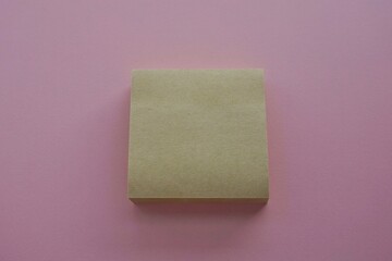 Yellow sticky post it note on a pink background