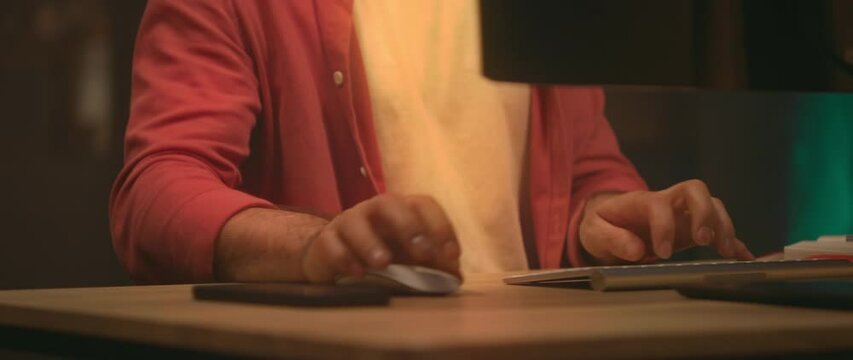 360 degree time-lapse. Footage of unrecognizable businessman working at computer in evening. Caucasian man typing actively on keyboard. Energetic moving around tracking shot. Blurred background of