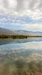 Fototapeta premium A quiet mountain lake Issyk-Kul, surrounded by green valleys and majestic mountains. The perfect spot for tourism and peaceful relaxation in Kyrgyzstan.