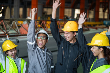 A group of construction workers are celebrating a job well done. They are all wearing hard hats and...