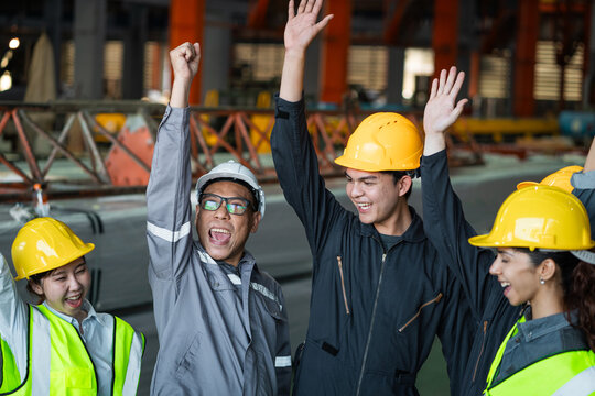 A group of construction workers are celebrating a job well done. They are all wearing hard hats and safety vests