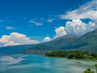 Breathtaking panoramic view of idyllic shore of Ohrid lake seen from St Naum monastery, North Macedonia. Surrounded by majestic mountains of National Park Galicica. Lush green hillsides. Mount Kota