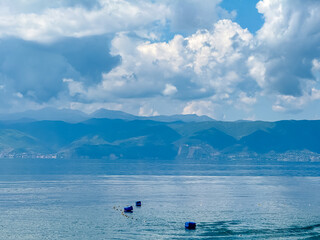 Obraz premium Serene lakeside scene along the shoreline of Lake Ohrid, North Macedonia. Mountain range of National Park Galicica in the distance. Slopes and hills covered with lush green vegetation and forest
