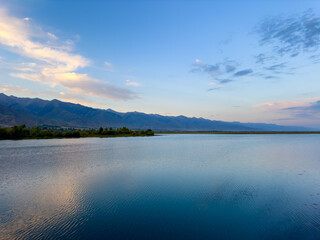 A wooden staircase leading into the clear waters of Issyk-Kul lake, with visible underwater vegetation. A perfect spot for water relaxation and enjoying nature