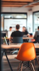 Modern office workspace with an orange chair and a collaborative atmosphere.
