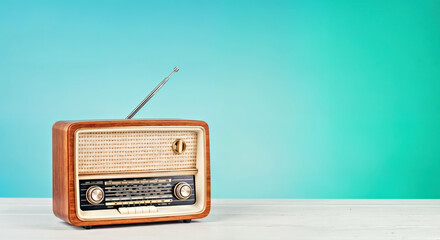 Obraz premium Vintage Radio on Wooden Table with Turquoise Background. World radio day concept