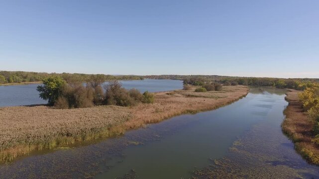 Drone pullback view of Mohawk River surrounded by fields on a sunny autumn day with a blue sky