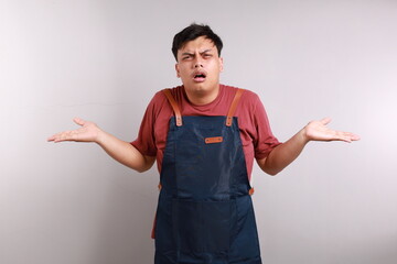 Photo image of funny Asian man in apron with shrug shoulder up gesture, showing i don't know or...