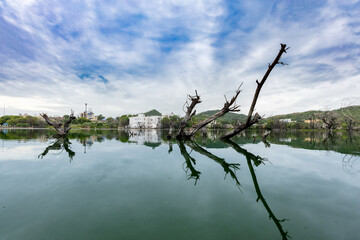 Naklejka premium Serene Lake with Mountain View and Wood water Reflections Under Bright dramatic Sky at morning