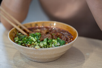 Close up yummy chinese lanzhou beef noodles and meat in brown bowl at noodle restaurant.